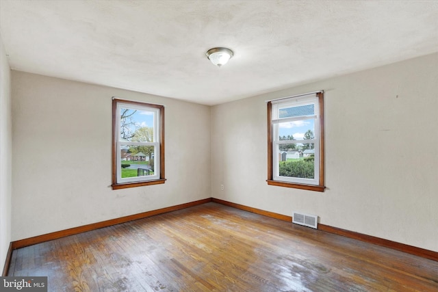 unfurnished room featuring wood finished floors, baseboards, and visible vents