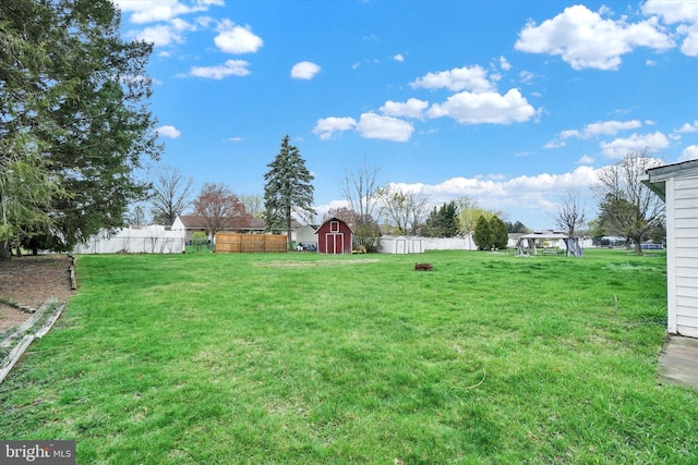 view of yard featuring an outbuilding, a storage unit, and fence