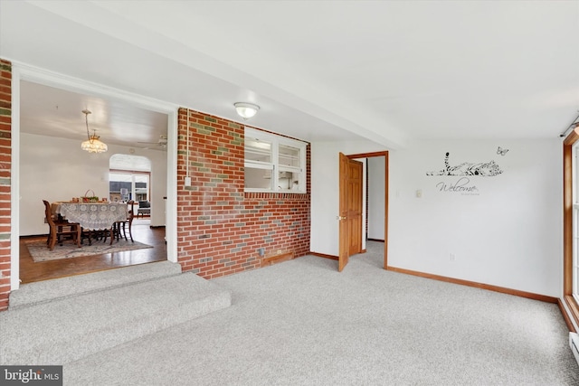 carpeted spare room with a baseboard radiator, baseboards, and an inviting chandelier