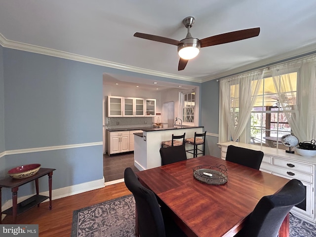 dining space with crown molding, a ceiling fan, baseboards, and dark wood finished floors