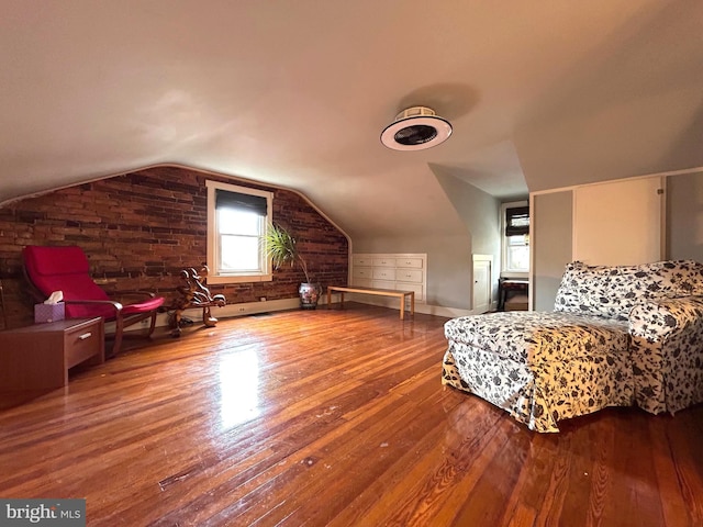 bedroom with baseboards, vaulted ceiling, hardwood / wood-style flooring, and brick wall