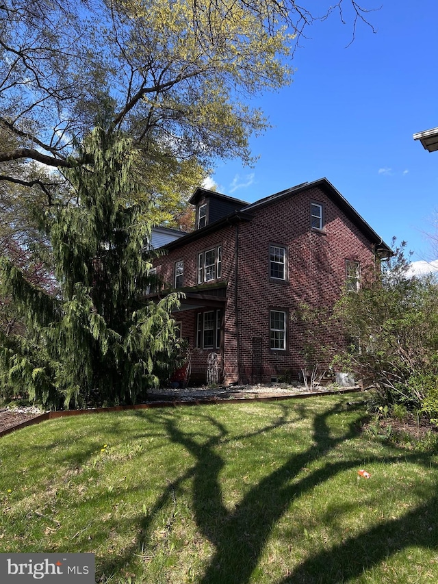 view of home's exterior with brick siding and a yard