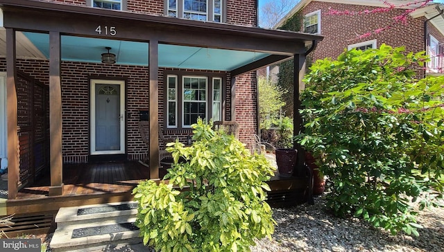 view of exterior entry with brick siding and covered porch
