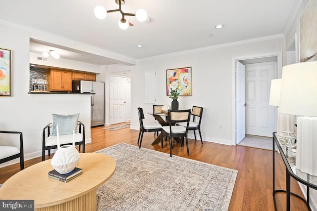 dining space with a chandelier, light wood-type flooring, baseboards, and ornamental molding