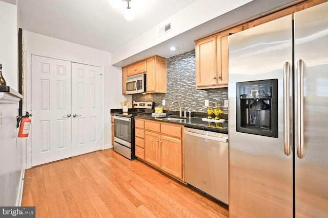 kitchen with light wood-style flooring, visible vents, a sink, stainless steel appliances, and decorative backsplash