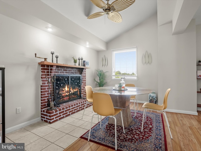 dining area with ceiling fan, a brick fireplace, vaulted ceiling, baseboards, and wood finished floors