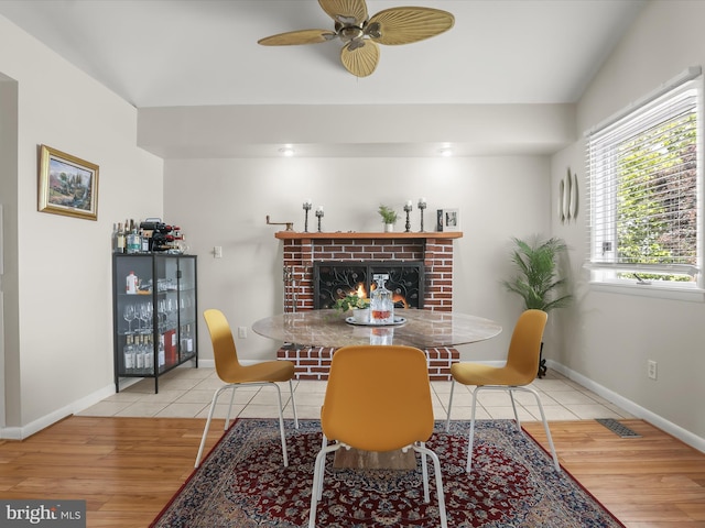 dining space featuring wood finished floors, ceiling fan, a fireplace, and baseboards