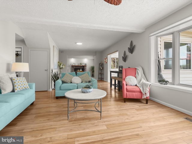 living room featuring a textured ceiling, light wood-style flooring, and baseboards