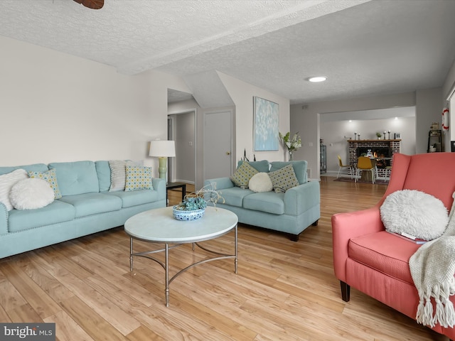living room with light wood-type flooring, a textured ceiling, and baseboards