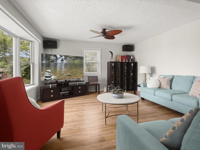 living room featuring a textured ceiling, a ceiling fan, wood finished floors, and healthy amount of natural light