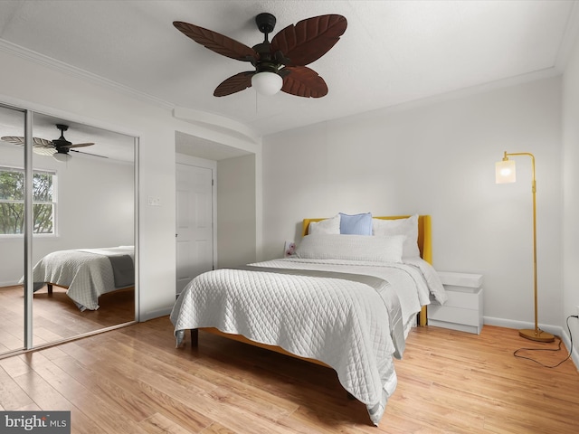 bedroom with wood finished floors, ornamental molding, a closet, ceiling fan, and baseboards