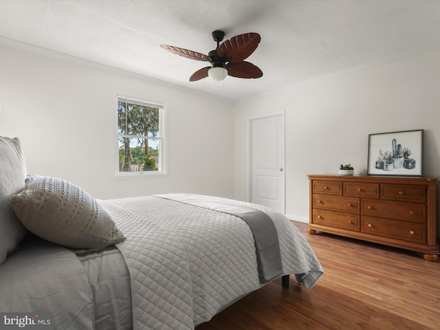 bedroom with light wood-style floors, ornamental molding, and a ceiling fan