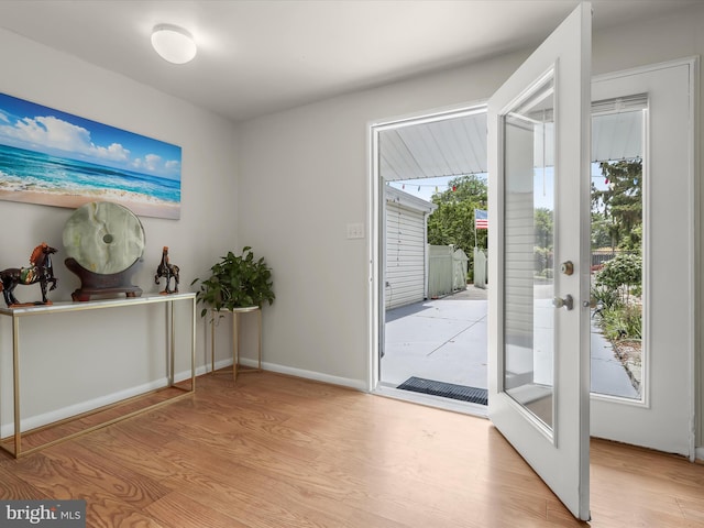 doorway to outside with light wood finished floors and baseboards