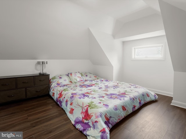 bedroom featuring dark wood-type flooring, vaulted ceiling, and baseboards