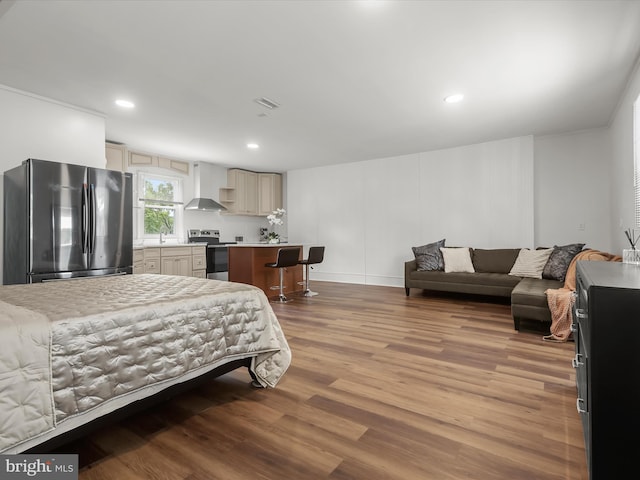 bedroom with freestanding refrigerator, wood finished floors, a sink, and recessed lighting