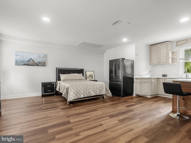 bedroom featuring freestanding refrigerator, wood finished floors, attic access, a sink, and recessed lighting