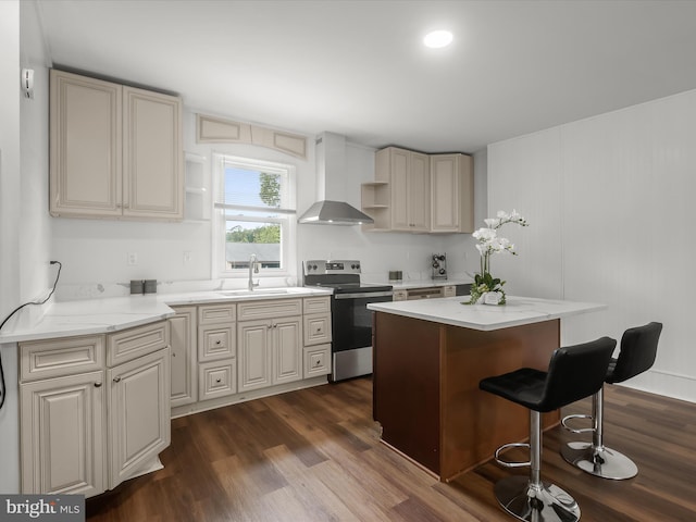 kitchen with electric range, wall chimney exhaust hood, a breakfast bar, dark wood finished floors, and a kitchen island