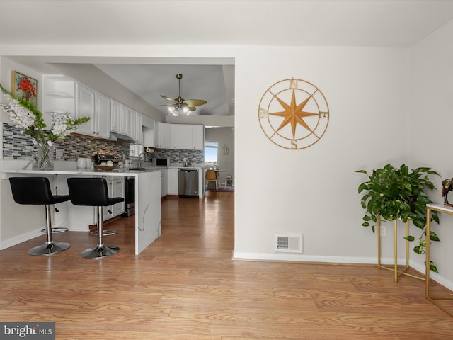 kitchen with dishwasher, a peninsula, decorative backsplash, light countertops, and open shelves