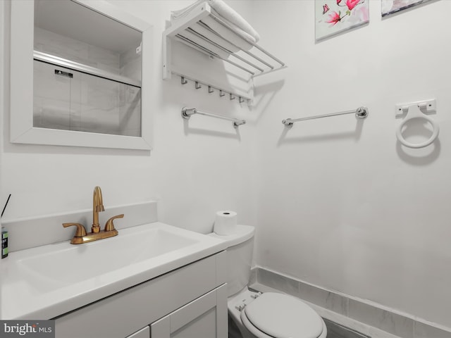 bathroom with toilet, vanity, and a shower with shower door