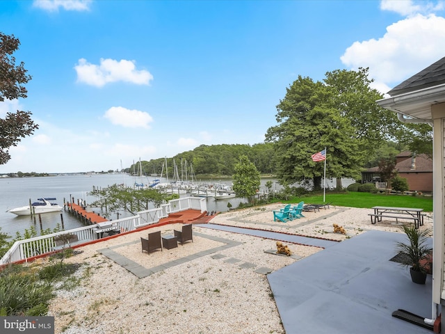 view of yard with a water view, a patio area, and a dock
