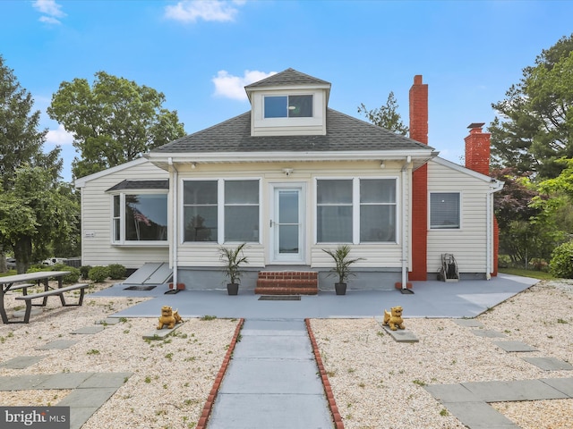 view of front of home featuring a patio, entry steps, and a shingled roof