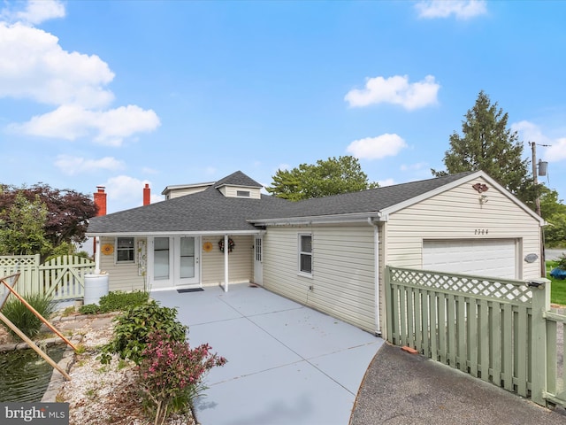 view of front of house with an attached garage, fence, a shingled roof, a chimney, and driveway
