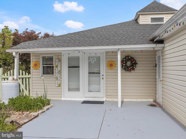 property entrance with roof with shingles and fence
