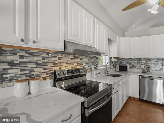 kitchen featuring appliances with stainless steel finishes, under cabinet range hood, a sink, white cabinets, and lofted ceiling