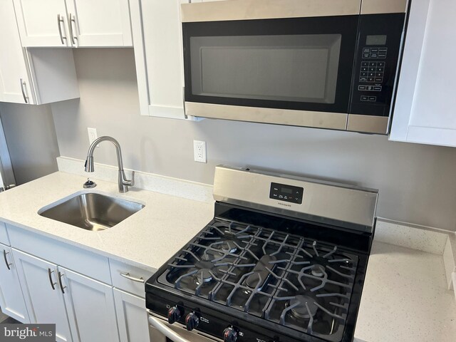 4301 Brehms Ln, Baltimore, MD 21206 - kitchen featuring appliances with stainless steel finishes, a sink, white cabinets, and light stone counters