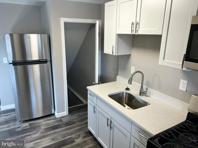 4301 Brehms Ln, Baltimore, MD 21206 - kitchen with appliances with stainless steel finishes, a sink, white cabinetry, dark wood finished floors, and light stone countertops