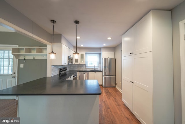 312 Fairgrove Ter, Gaithersburg, MD 20877 - kitchen featuring stainless steel appliances, dark countertops, a peninsula, dark wood-style floors, and decorative backsplash
