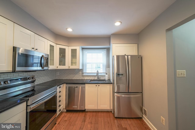 312 Fairgrove Ter, Gaithersburg, MD 20877 - kitchen featuring appliances with stainless steel finishes, dark countertops, light wood-type flooring, tasteful backsplash, and recessed lighting