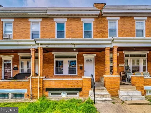 townhome / multi-family property featuring a porch and brick siding