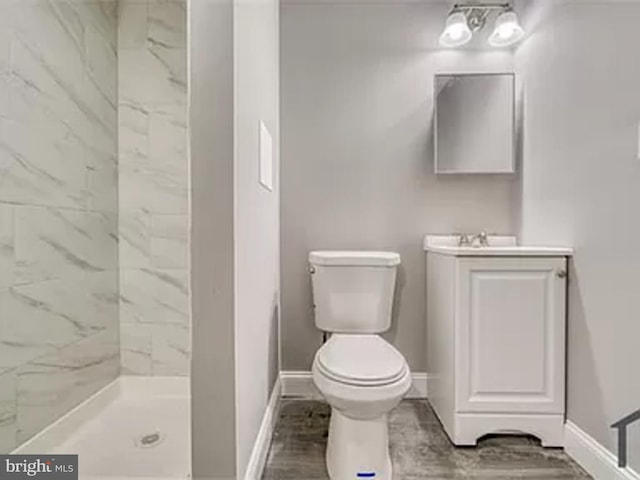 bathroom with toilet, baseboards, vanity, walk in shower, and wood finished floors