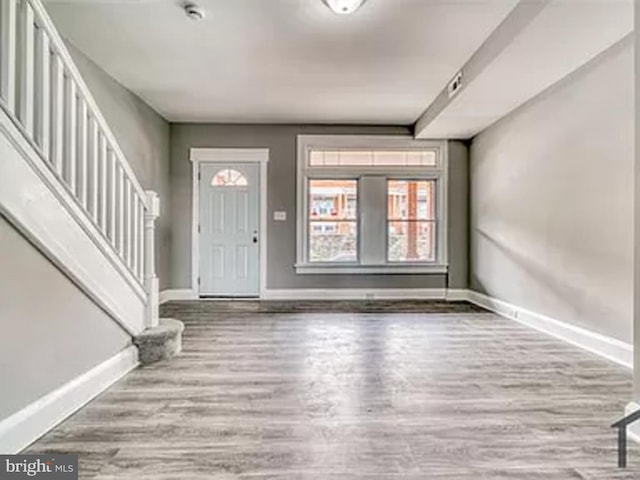 entryway with baseboards, wood finished floors, and stairway