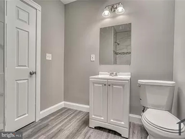 bathroom with baseboards, wood finished floors, toilet, and vanity