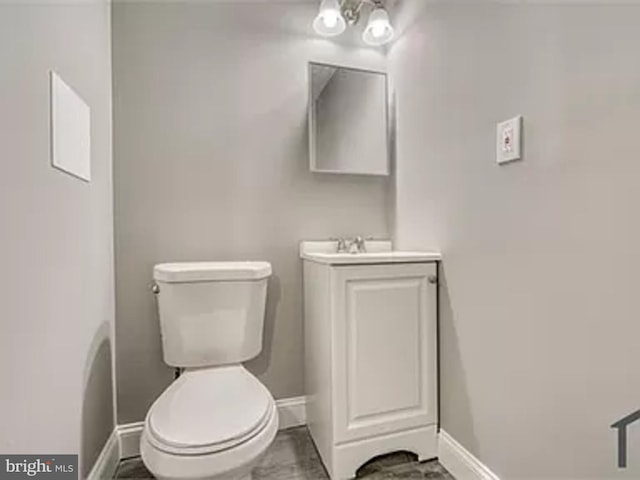 bathroom featuring baseboards, toilet, and vanity