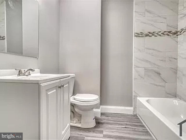 bathroom featuring toilet, baseboards, vanity, and wood finished floors
