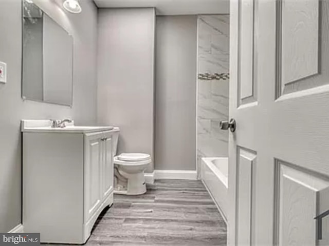 full bathroom featuring vanity, toilet, wood finished floors, baseboards, and bathtub / shower combination
