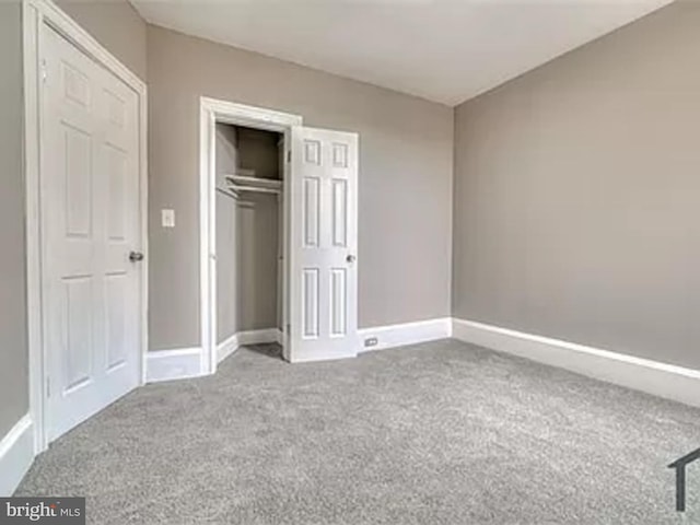 unfurnished bedroom featuring carpet floors, baseboards, and a closet