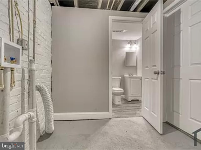 bathroom featuring concrete flooring, toilet, and baseboards