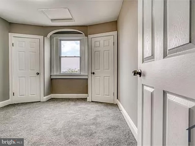 unfurnished bedroom featuring carpet floors, attic access, and baseboards