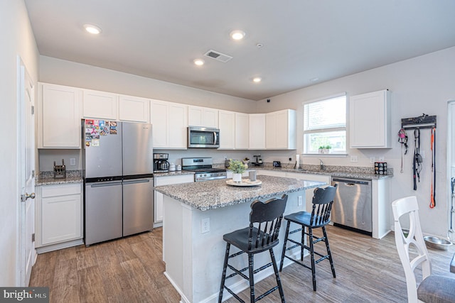 417 Lena Ln, Fruitland, MD 21826 - kitchen featuring light wood-style flooring, white cabinetry, a kitchen bar, light stone counters, and appliances with stainless steel finishes
