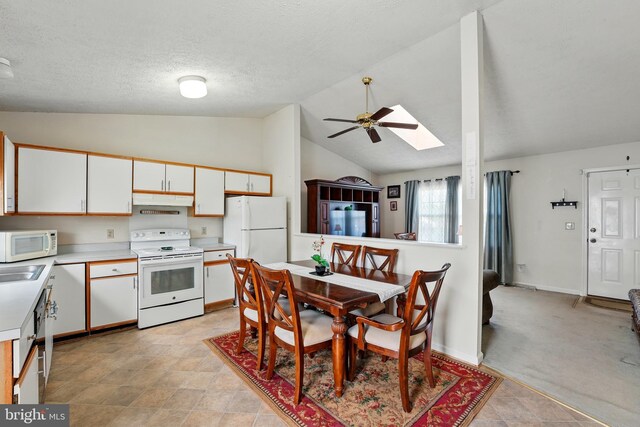 6775 Rugby Pl, Bealeton, VA 22712 - kitchen featuring white appliances, light countertops, white cabinetry, under cabinet range hood, and vaulted ceiling with skylight