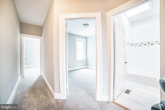 hall featuring visible vents, baseboards, and carpet flooring