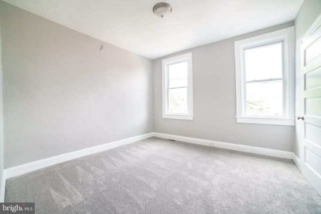 carpeted spare room featuring baseboards