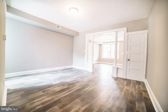 spare room featuring visible vents, baseboards, and dark wood finished floors