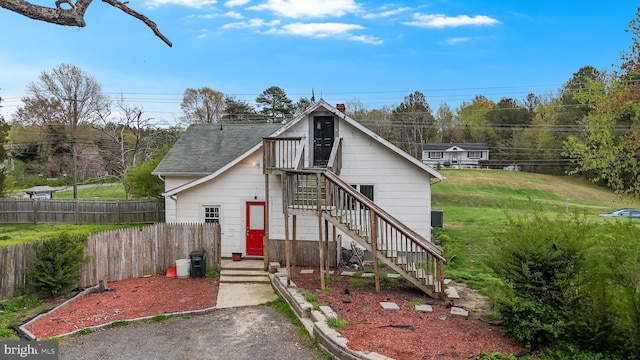 exterior space featuring a front yard, fence, a shingled roof, and stairs