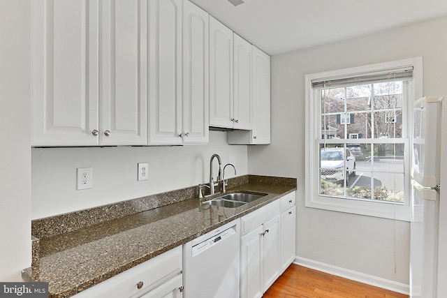 kitchen with white cabinetry, light wood finished floors, a sink, and white appliances