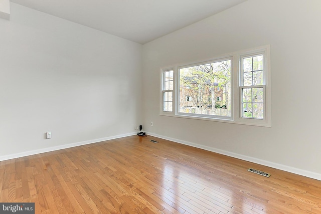 spare room featuring visible vents, light wood finished floors, and baseboards